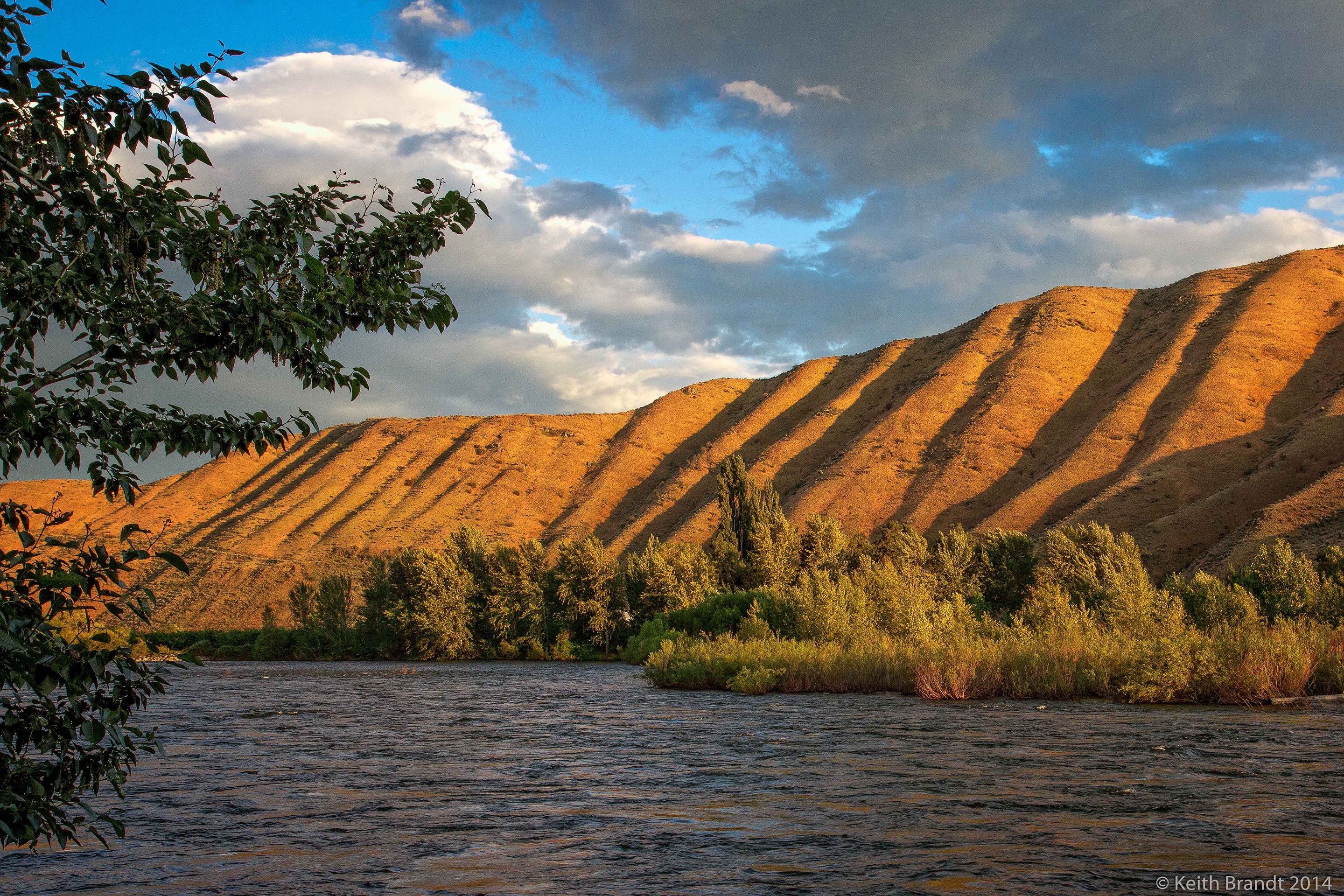 Une rivière bordée de montagnes et entourée d’une végétation luxuriante.