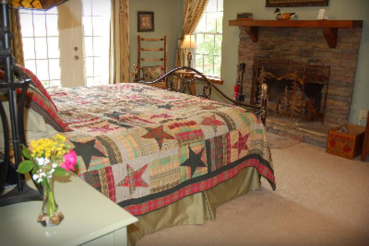 A bedroom with a large bed, a fireplace, and a window with curtains.