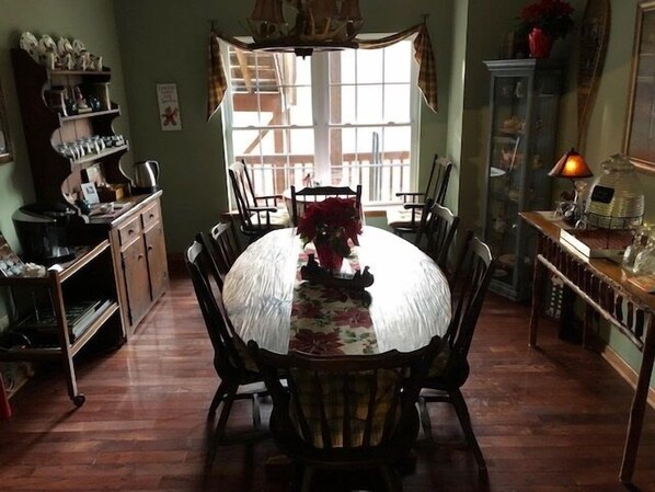 A dining area with a round table, chairs, and a window with curtains. - Long Mountain Lodge (Dahlonega)