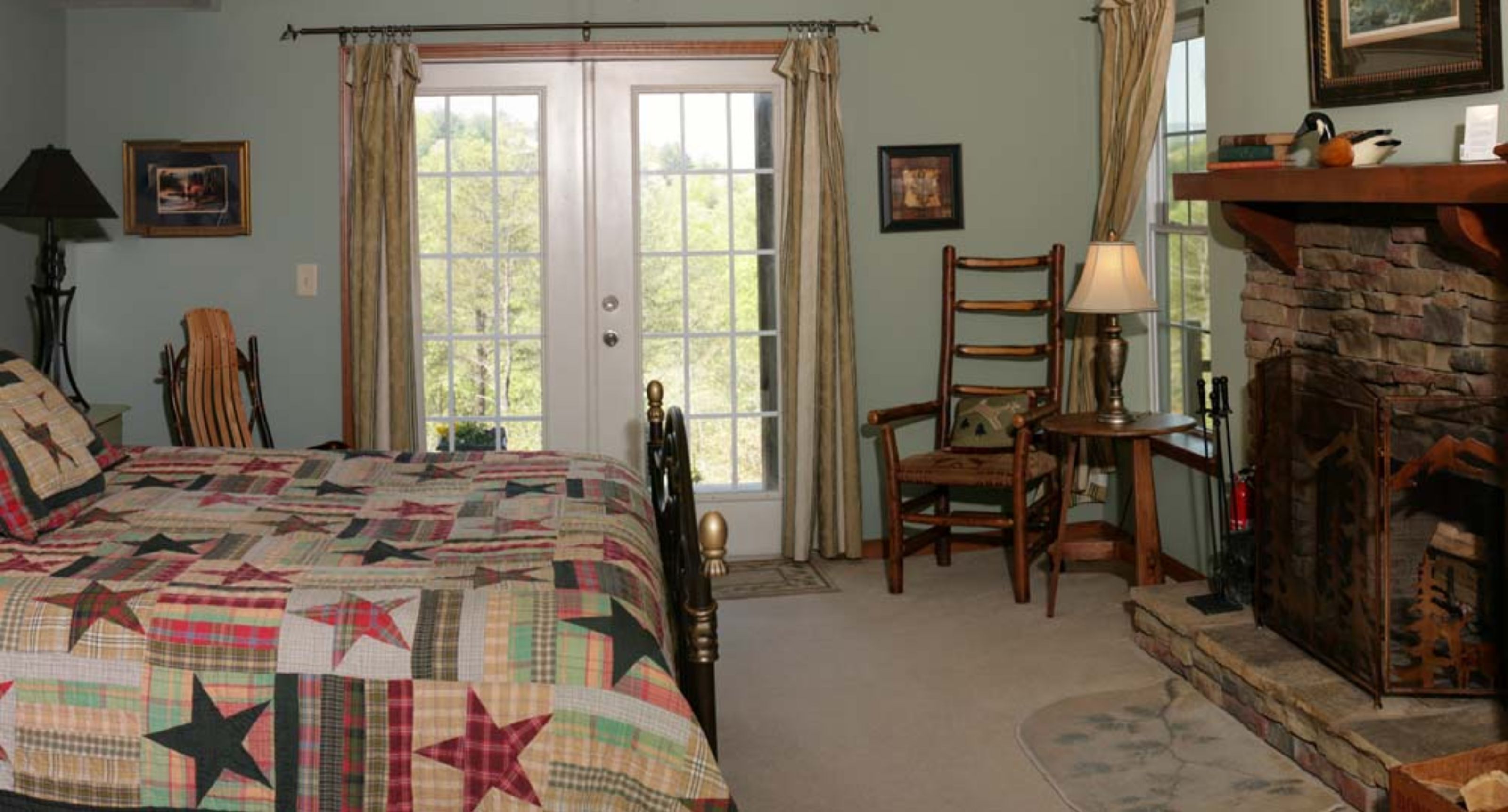A bedroom with a large bed, a fireplace, a chair, and a door with curtains.