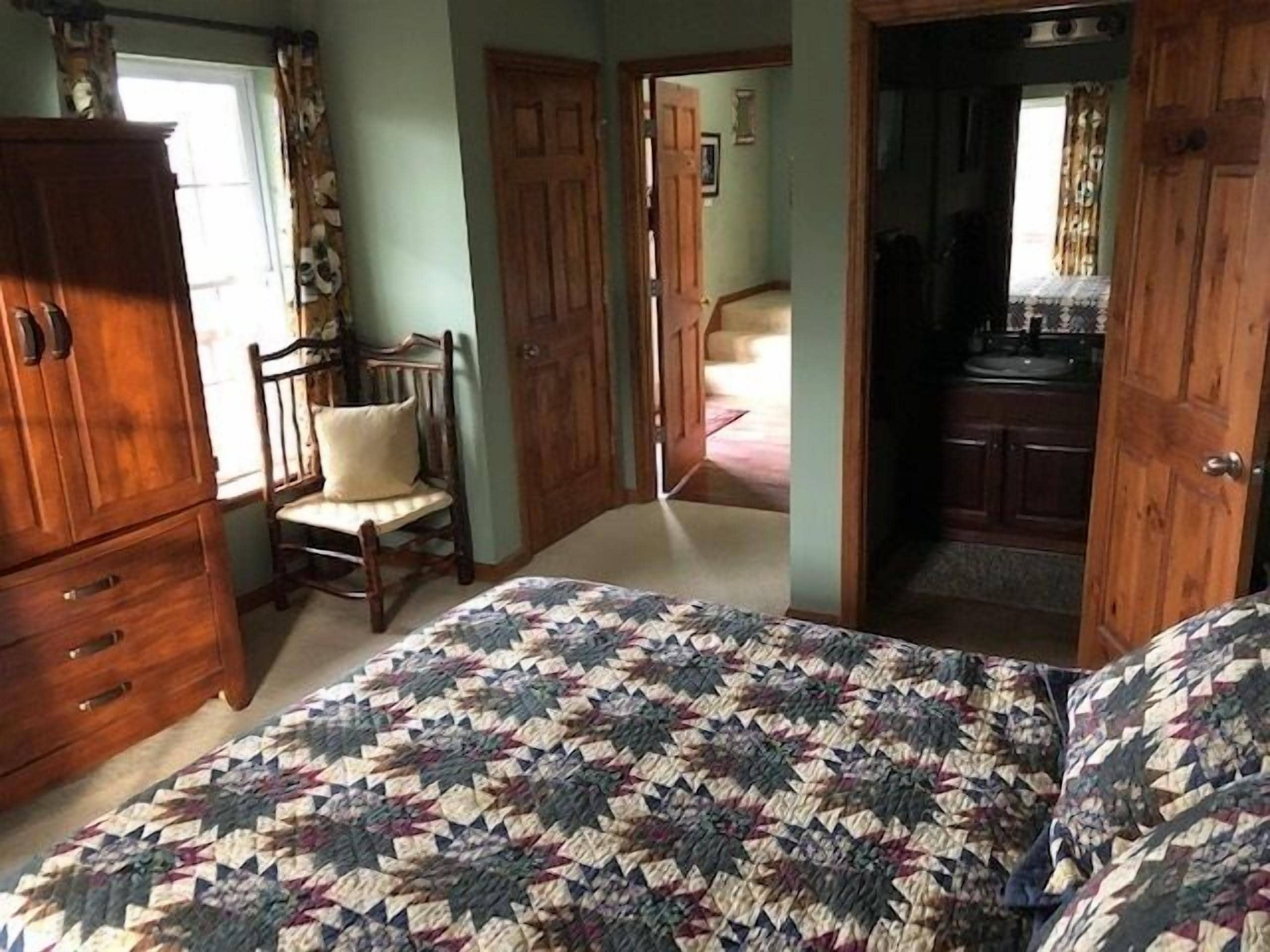 Un dormitorio con cama, armario de madera y una silla.