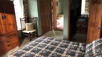 Un dormitorio con cama, armario de madera y una silla.