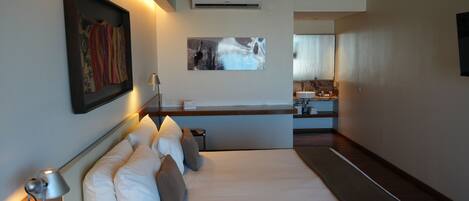 Een hotelkamer met een bed, een bureau, een spiegel en kunstwerken aan de wanden.