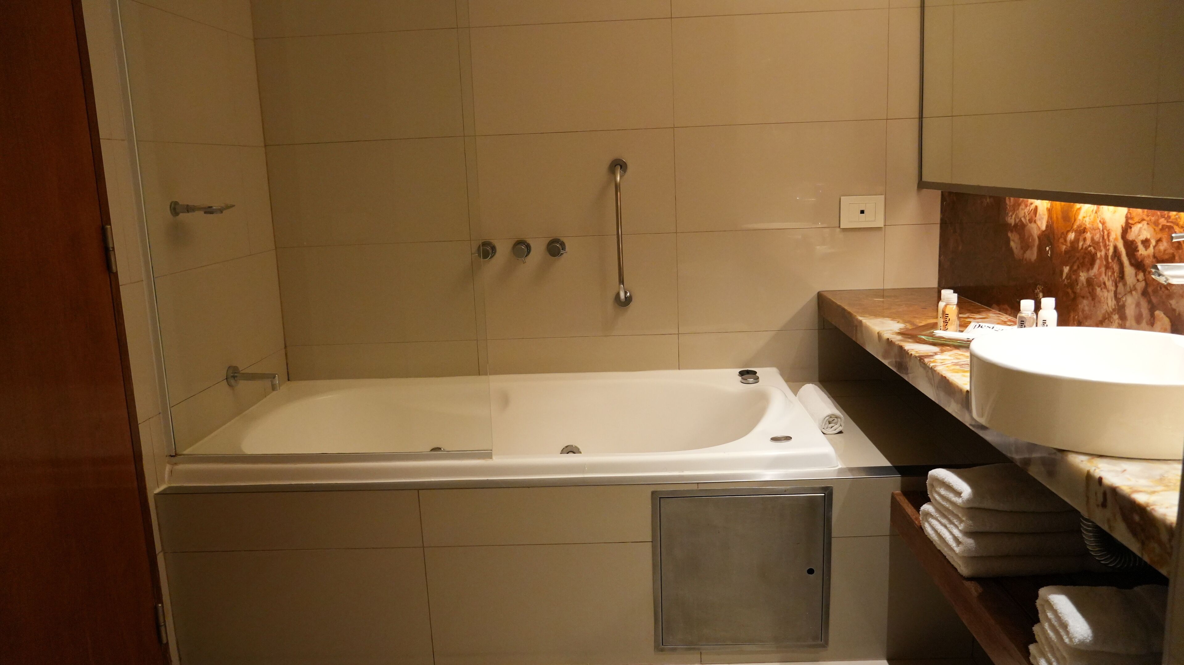 Un baño con bañera, lavamanos y tocador con artículos de aseo.