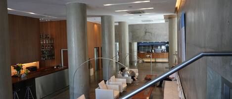 A modern lobby with a reception desk, seating area, and a bar.