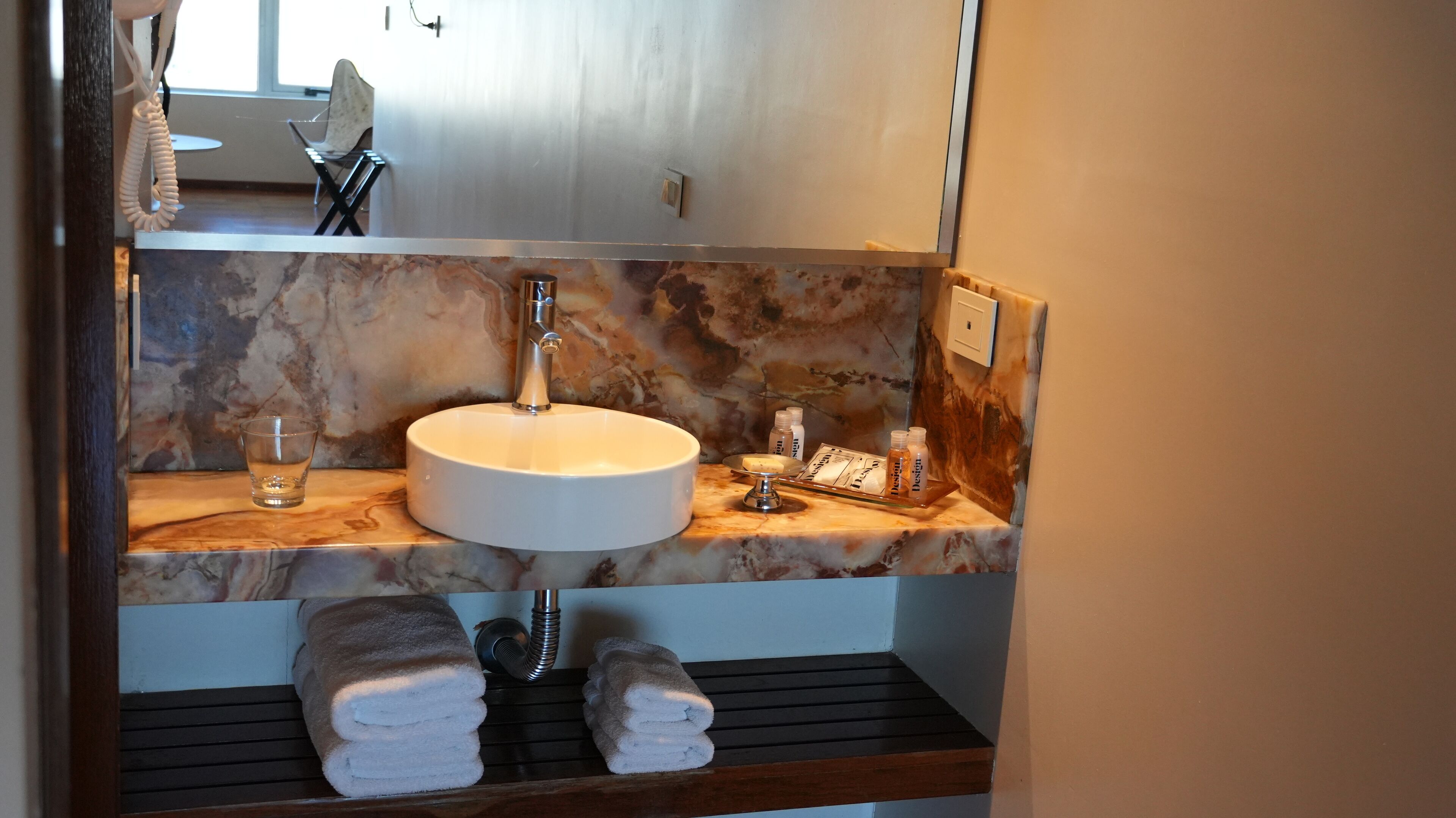 A bathroom with a marble sink, a mirror, and a towel rack.