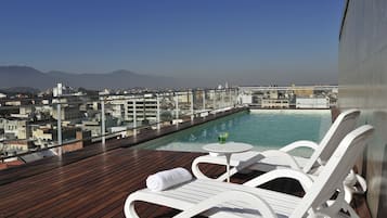 Una piscina al aire libre, sillones reclinables de piscina