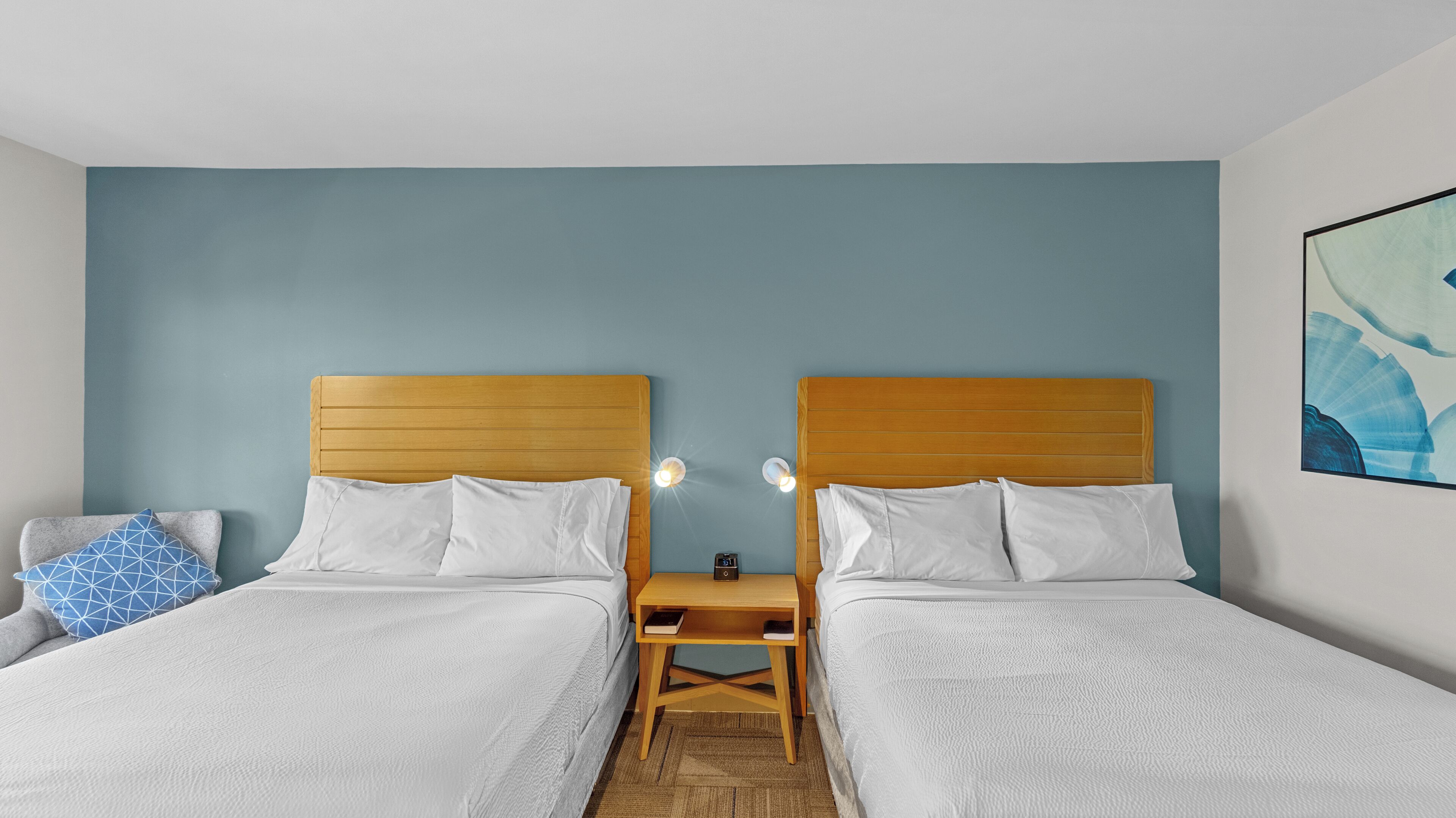 A twin room with two beds, a nightstand, and a wall clock.