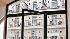 A room with a large window overlooking a building with balconies and outdoor seating. - Hotel Angelis (Prague)