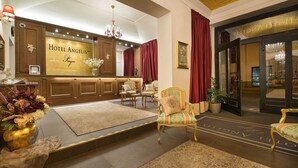A hotel lobby with a reception desk, seating area, and a large chandelier. - Hotel Angelis (Prague)