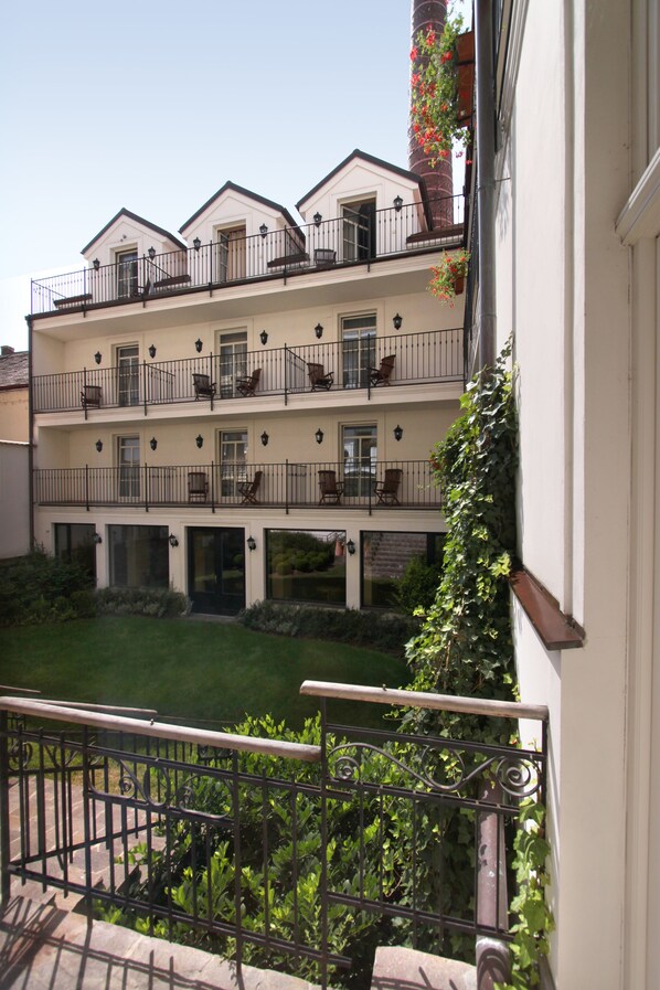 Un hôtel à plusieurs étages doté de balcons, d’un jardin et d’une cheminée en briques.