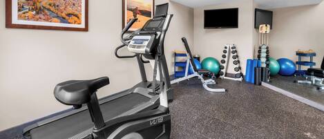 A gym with a treadmill, exercise bike, and various fitness equipment.