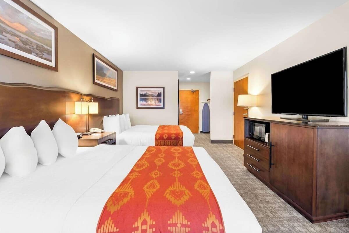 Een hotelkamer met twee bedden, een televisie, een bureau met lamp en een kledingkast.