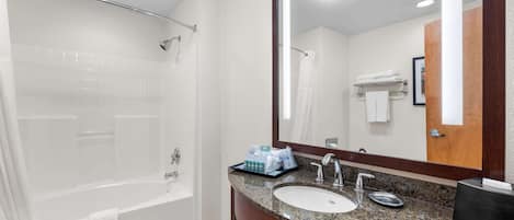 Un baño moderno con una bañera, un lavabo y un espejo grande.