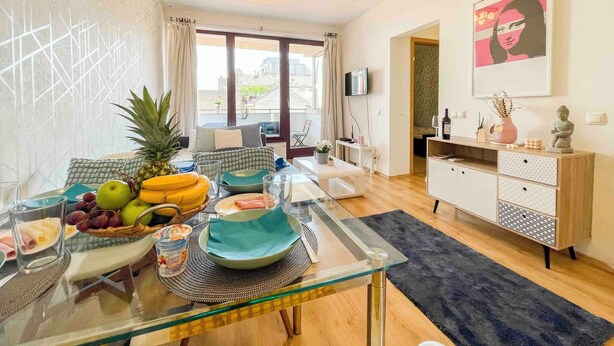 A modern living room with a glass dining table, a sofa, and a TV. - Opera Residence (Budapest)