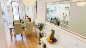 A modern living room with a dining area, a large mirror, and a fruit bowl on a console table. - Opera Residence (Budapest)