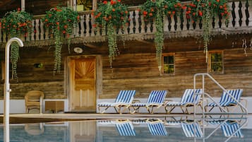 Una piscina al aire libre, sillones reclinables de piscina