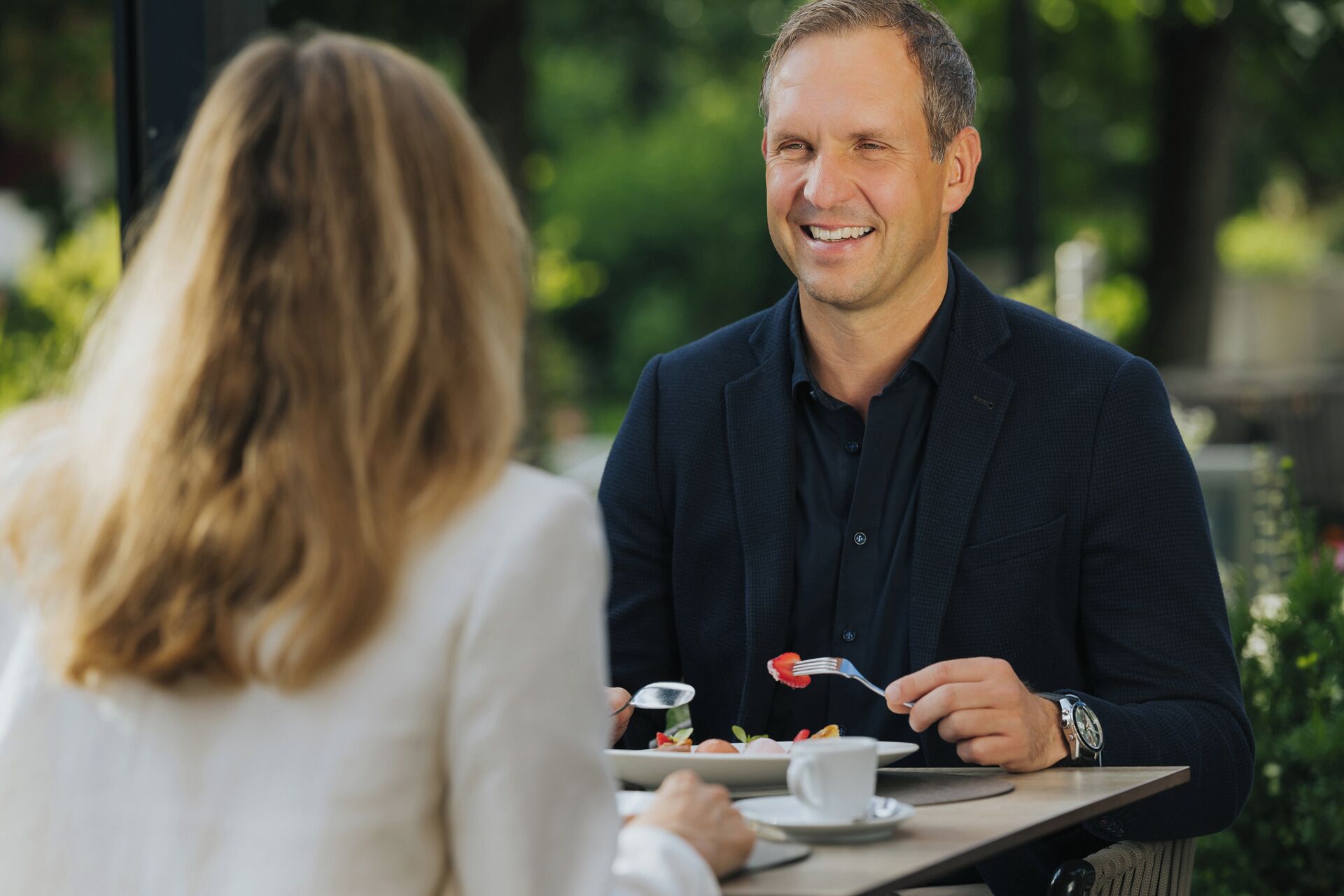 Iemand zit aan een tafel met een bord eten, een beker en een vork.