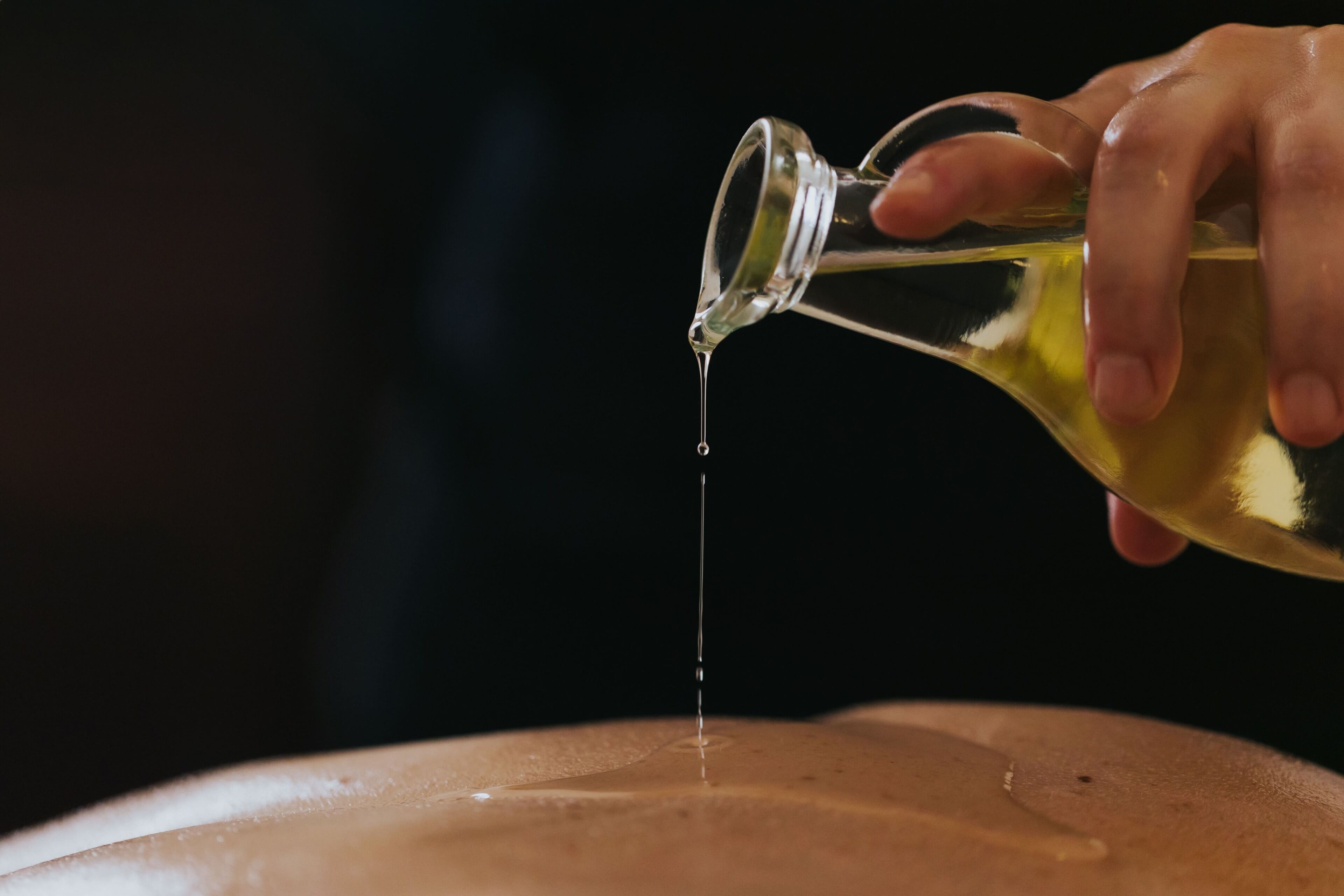 A hand pouring a clear liquid from a bottle onto a flat surface.
