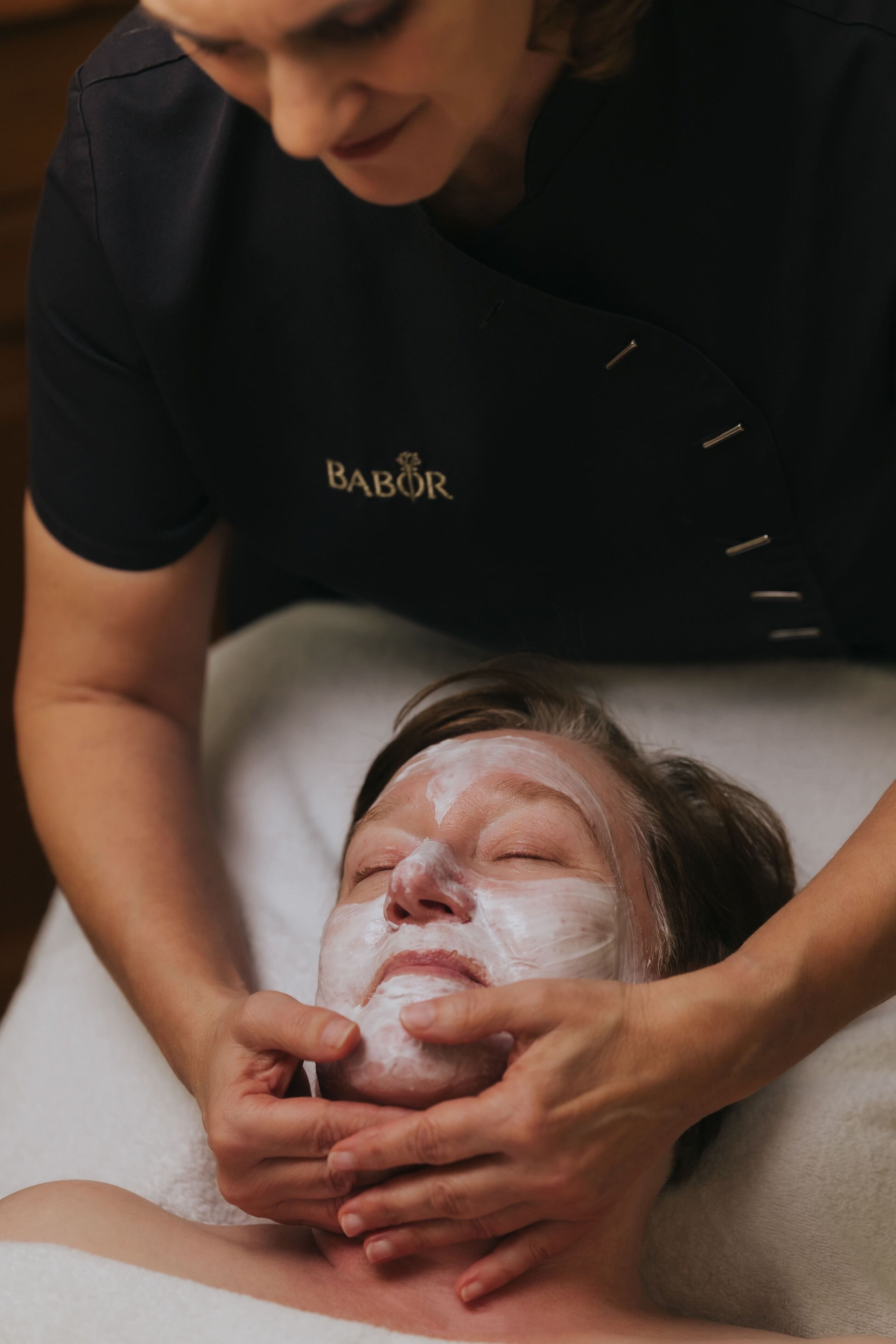 A person receiving a facial treatment with a focus on the hands and the face.