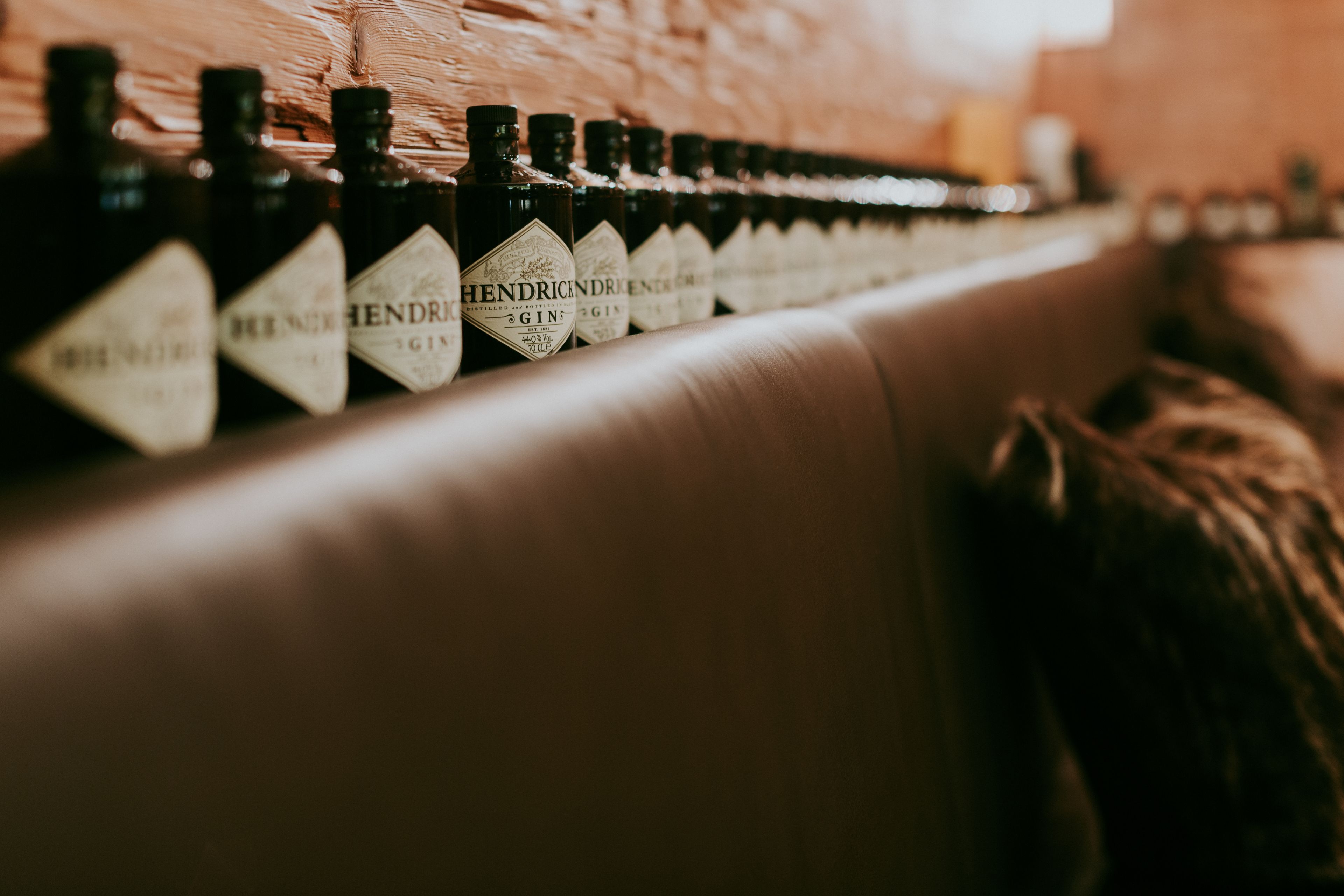 Een rij flessen met de tekst 'Hendrick's Gin' op een plank.
