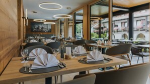 A restaurant with wooden tables, white napkins, and modern pendant lighting. - Hotel Drei Quellen Therme (Bad Griesbach im Rottal)