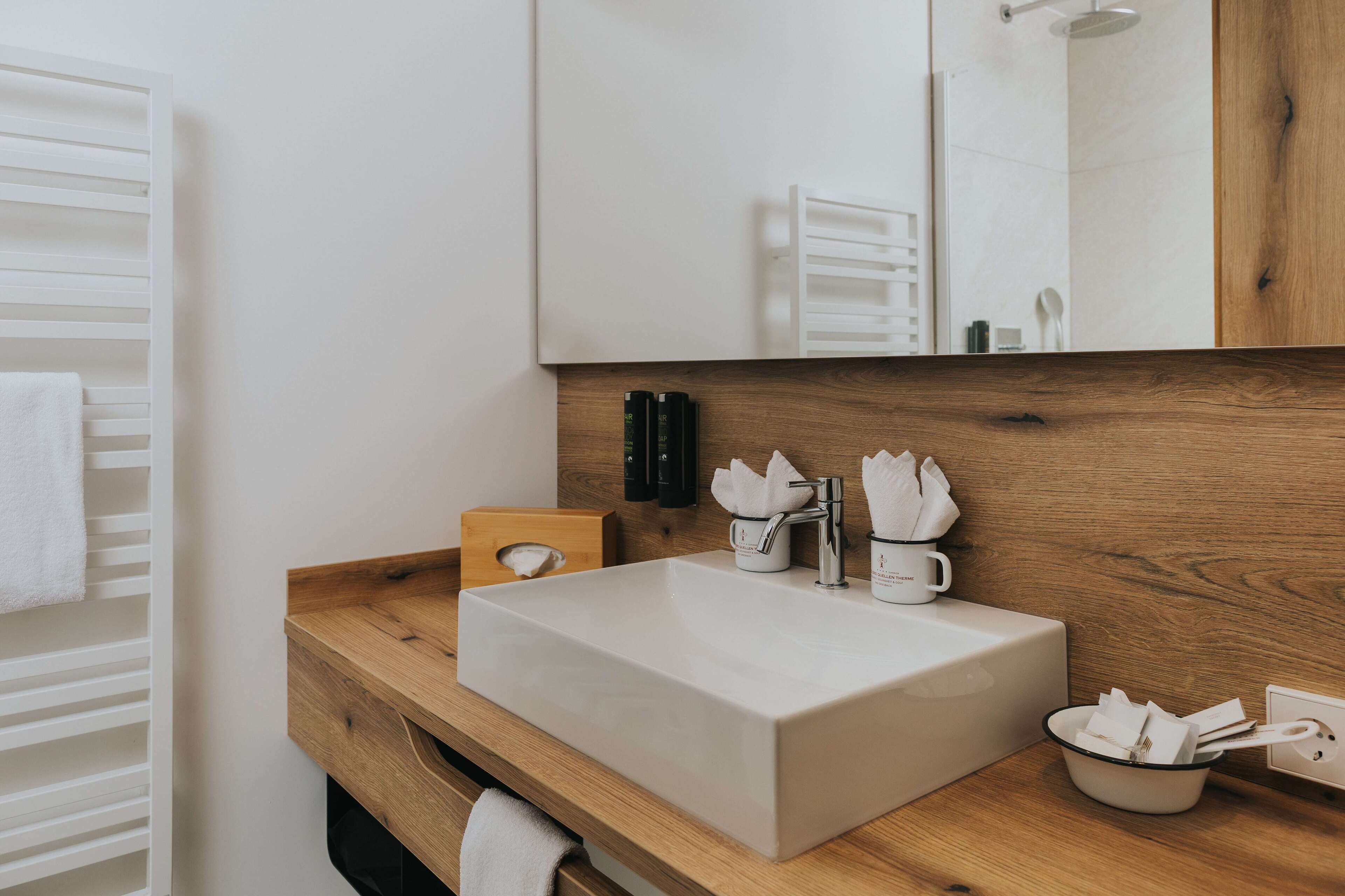 A modern bathroom with a large rectangular sink, wooden countertop, and a mirror above.