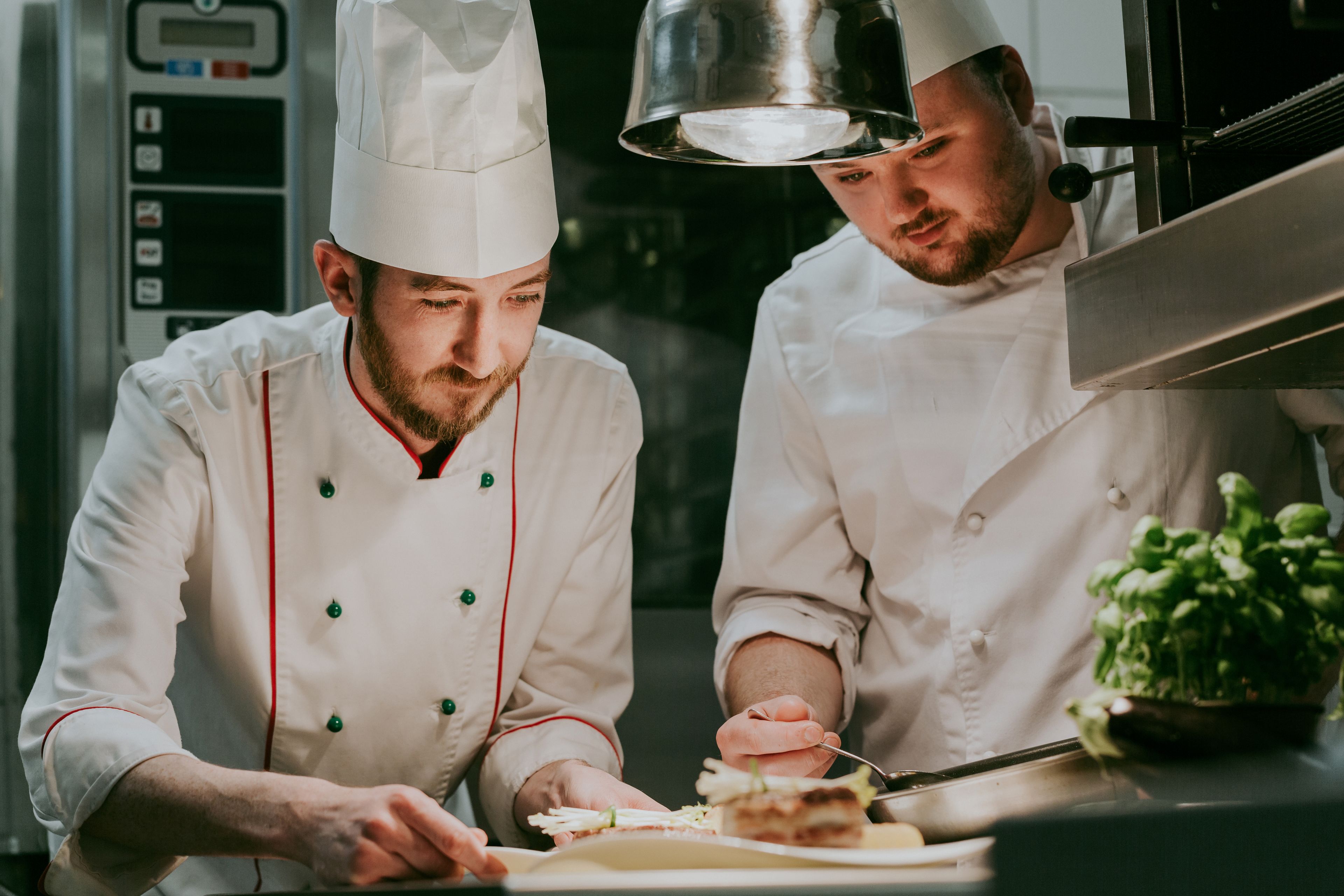 Two chefs in a professional kitchen, preparing food.