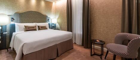A hotel room with a large bed, a chair, a nightstand, and a lamp.