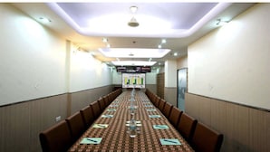 Una sala conferenze con un lungo tavolo, sedie e uno schermo per proiettore nella parte anteriore.