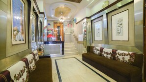 Un'hall d'albergo con una reception, una scala e zone salotto.