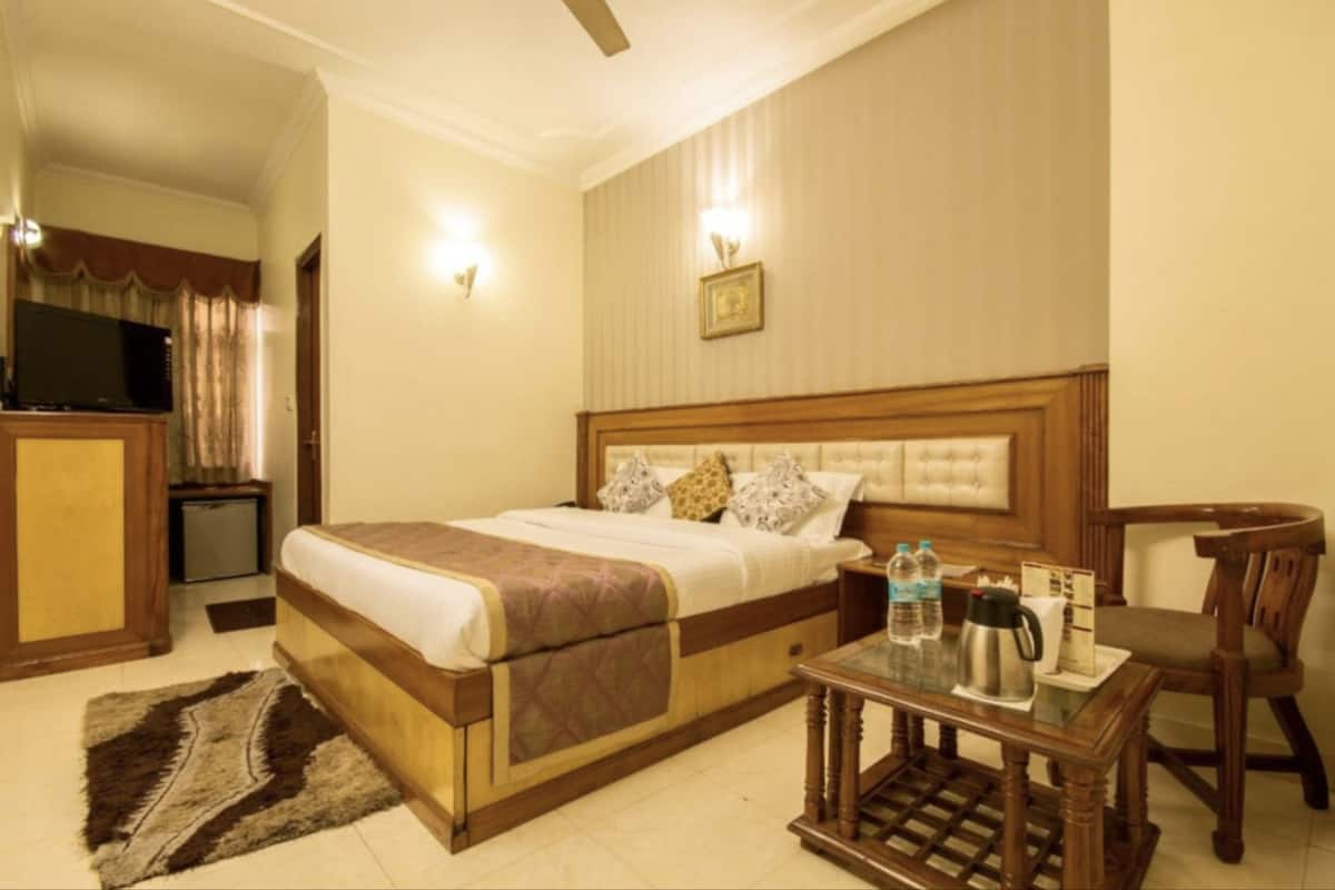 A hotel room with a bed, bedside table, chair, and a television.
