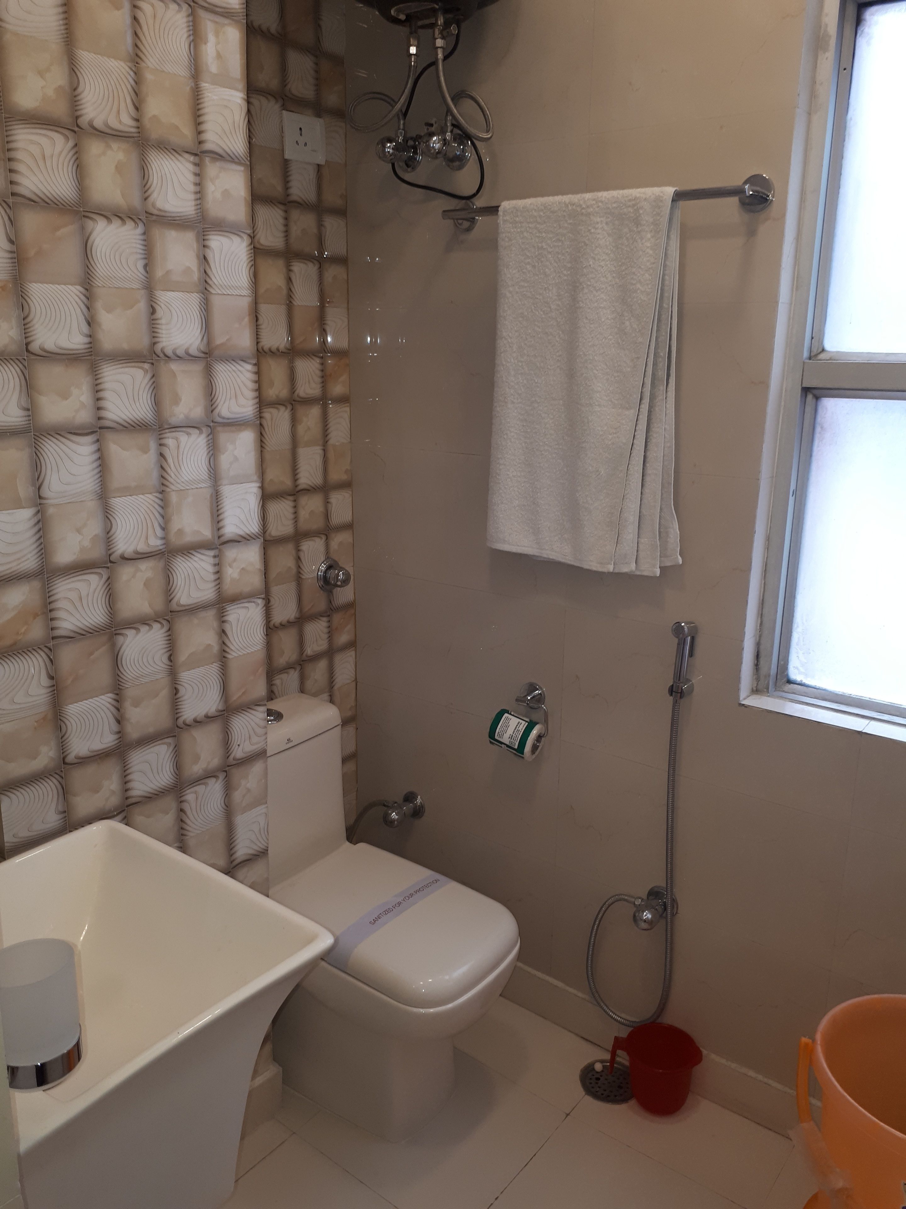 Ein Badezimmer mit Toilette, Dusche, Handtuchhalter und einem Fenster.