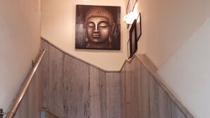 A staircase with wooden steps and a Buddha head sculpture above it. - Hotel lals Haveli (New Delhi)