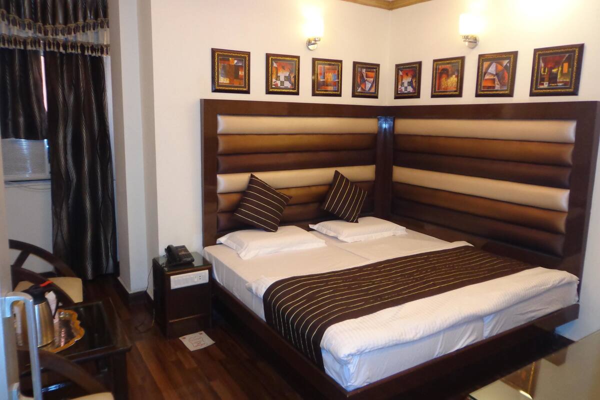 A hotel room with a large bed, a bedside table with a phone, and a chair.