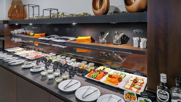 Monipuolinen buffet, jossa on tarjolla erilaisia ruokia ja lisukkeita, kuten hedelmiä, vihanneksia ja kastikkeita.