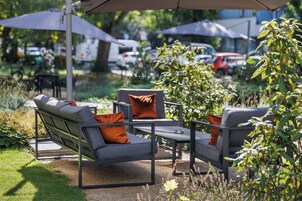 Un área de estar al aire libre con muebles modernos y sombrillas.