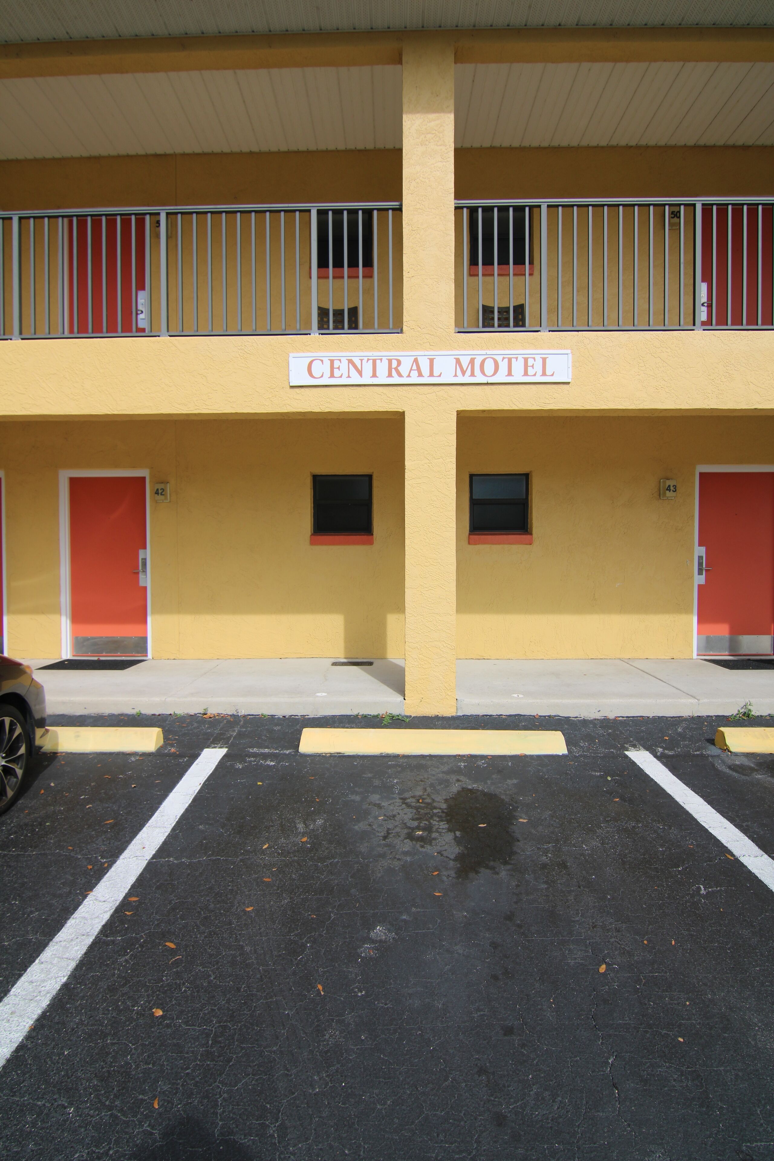 A two-story motel with numbered doors, a parking lot, and a sign reading "Central Motel".