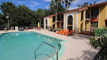 Una piscina al aire libre, sombrillas, sillones reclinables de piscina