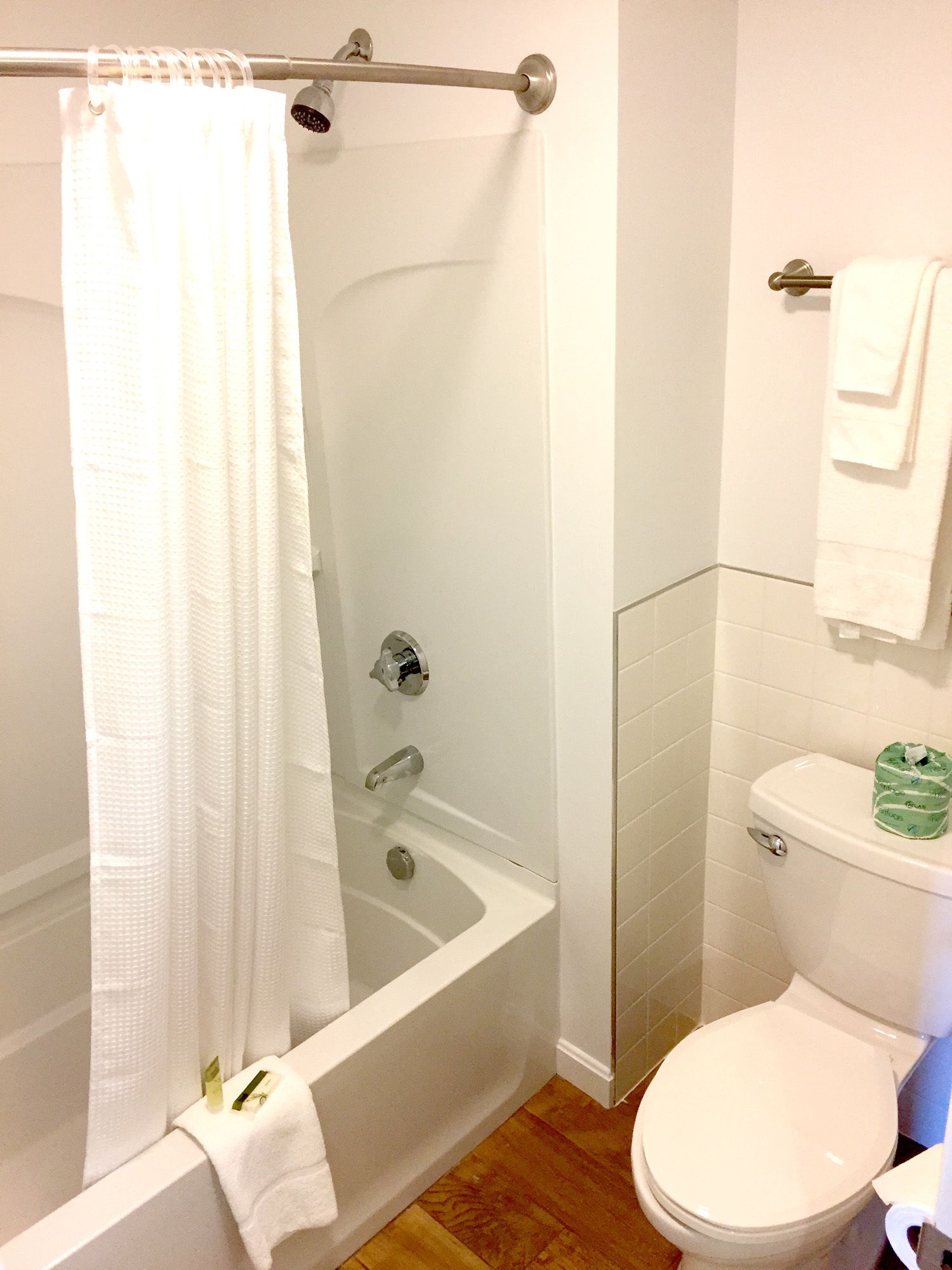 A bathroom with a bathtub, toilet, and a glass shower enclosure.