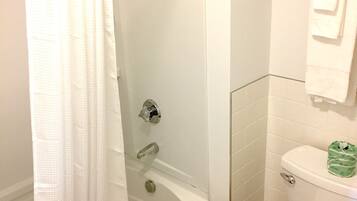 A bathroom with a bathtub, toilet, and a glass shower enclosure.