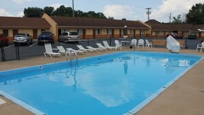 A motel with a swimming pool, multiple lounge chairs, and a parking lot. - Andrew Johnson Inn (Greeneville)