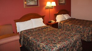 A hotel room with two beds, a chair, a lamp, and two paintings on the wall. - Andrew Johnson Inn (Greeneville)