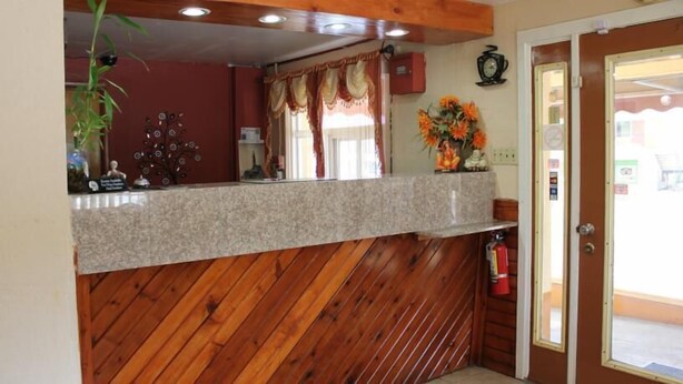 A reception area with a wooden counter, a fire extinguisher, and a window with curtains. - Andrew Johnson Inn (Greeneville)