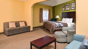 A hotel room with a sofa, a bed, a small table, and a chair.