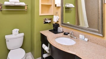 A bathroom with a toilet, sink, and mirror. There are towels on a rack and a shelf.