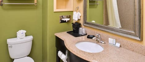 A bathroom with a toilet, sink, and mirror. There are towels on a rack and a shelf.