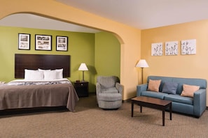 A hotel room with a bed, a sofa, a chair, a coffee table, and framed pictures on the walls. - Sleep Inn & Suites Downtown Houston Near Convention Center (Houston)