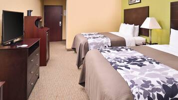 A hotel room with two beds, a TV, a dresser, and a door leading to another room.