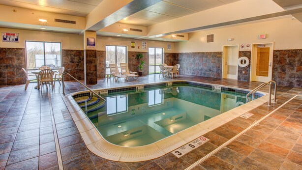 An indoor swimming pool with a tiled floor, a lifeguard chair, and a pool ladder.